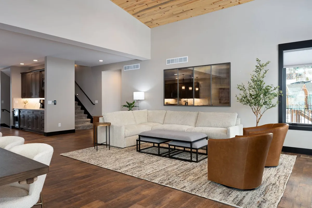 A spacious lounge area featuring a sectional sofa, coffee table, and a TV unit, with large windows that fill the room with light. The setup suggests a comfortable environment ideal for socializing, relaxing, or enjoying entertainment after a day of activities.