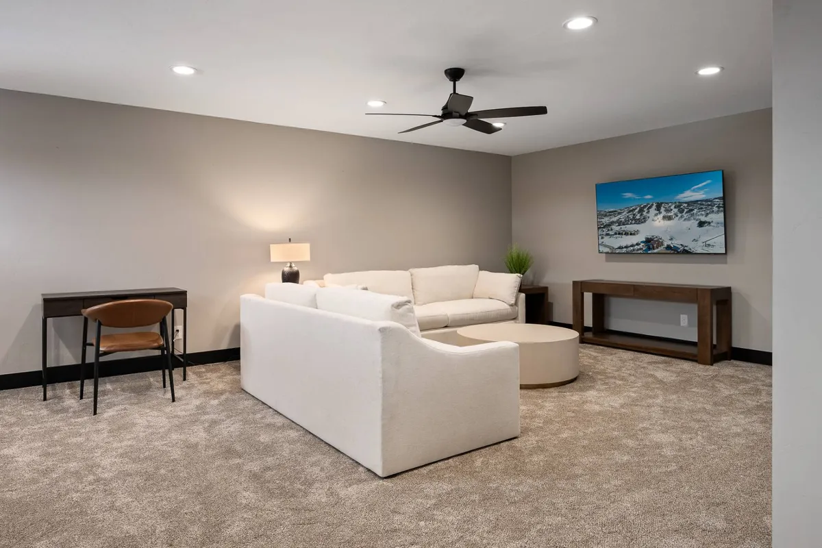 A cozy room showcasing a sofa, coffee table, TV, and desk area. The setup is casual and inviting, suggesting an ideal spot for friendly gatherings, casual game nights, or a quick board game setup in between adventures.