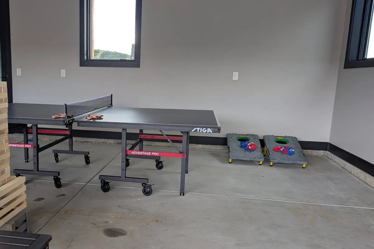 A dedicated game area with a ping pong table and cornhole boards, set up for playful competitions and social fun. The space is open and casual, encouraging friendly rivalry and group activity.