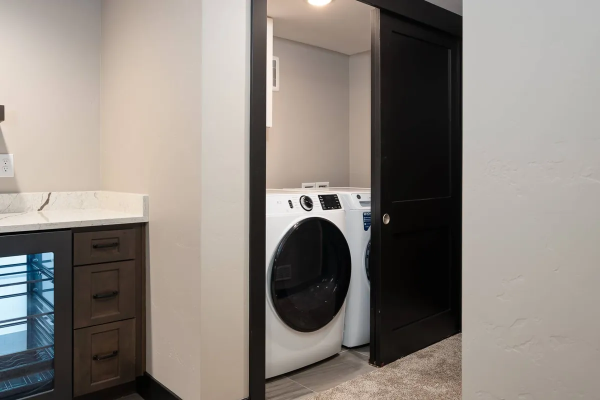 A functional laundry area with a washing machine, drying machine, countertop, and cabinetry. The space is organized and practical, reflecting thoughtful design for everyday needs.